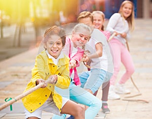 Company of kids are playing in tug of war