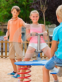 Company of kids are teetering on the swing photo