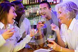 Company of multiracial friends drinking beer and talking with each other during the rest in a pub