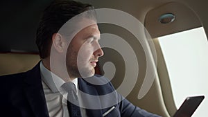 Company owner using tablet at airplane window closeup. Stressed man contemplate