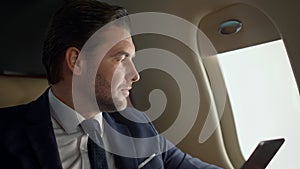 Company owner using tablet at airplane window closeup. Stressed man contemplate