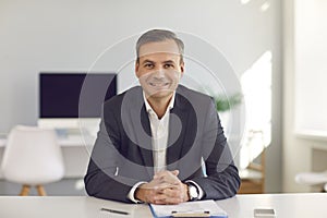 Company's manager sits at a desk in the office and holds an online meeting with his clients.