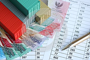 Company shipping cargo containers in Indonesia with rupiah money bills and pen