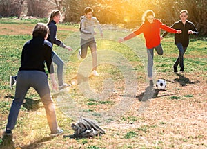 Company of teenagers playing football in park