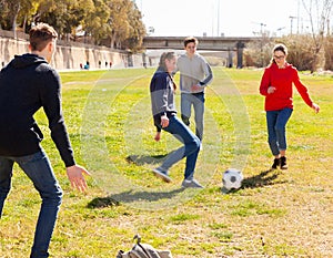 Company of teenagers playing football in park