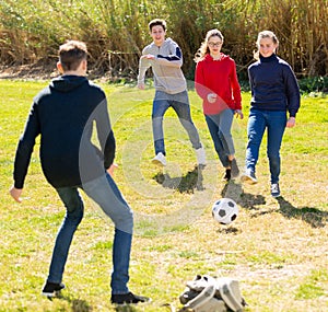 Company of teenagers playing football in park