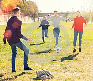 Company of teenagers playing football in park