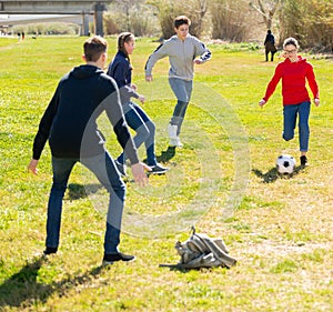 Company of teenagers playing football in park