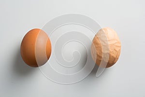 Compare brown asian egg and ugly abnormal egg on grey background. View from above