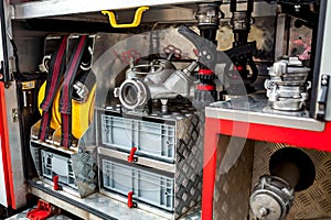 Compartment of rolled up fire hoses on a fire engine. Rescue fire truck equipment. A silver fire hydrant with red valves and other
