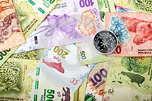 Compass on Argentine currency notes from a top view. photo
