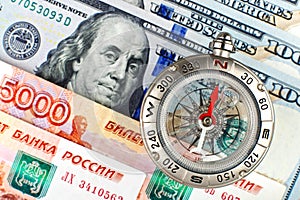 Compass with arrow pointing up on the background of Russian and American banknotes