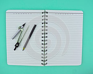 Compass and a black pen on top of a open note paper diary isolated on a white background