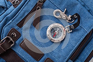 Compass and blue travel backpack, tourist items close-up, magnetic compass with metal clasp