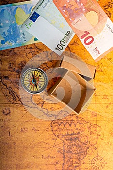 Compass beside a box and Euro banknotes  on an old map