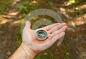 Compass in hand at forest. Tourist compass for orientation on the terrain. Magnetic declination Ñalculator. Historical explorer