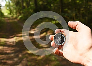 Compass in hand at forest. Tourist compass for orientation on the terrain. Magnetic declination Ñalculator. Historical explorer