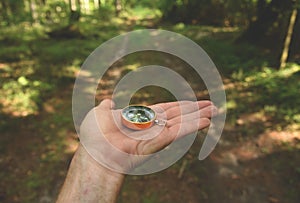 Compass in hand at forest. Tourist compass for orientation on the terrain. Magnetic declination alculator. Historical explorer