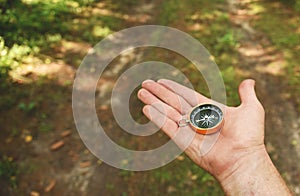 Compass in hand at forest. Tourist compass for orientation on the terrain. Magnetic declination alculator. Historical explorer