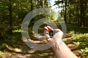 Compass in hand at forest. Tourist compass for orientation on the terrain. Magnetic declination alculator. Historical explorer