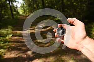 Compass in hand at forest. Tourist compass for orientation on the terrain. Magnetic declination alculator. Historical explorer