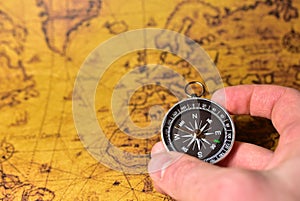 Compass in hand on map. Tourist compass for orientation on the terrain. Magnetic declination Ñalculator. Historical explorer help