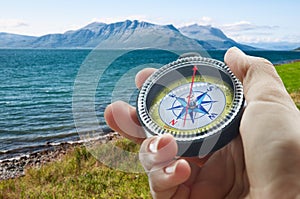 Compass and hand in mountains