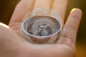 Compass in hand on natural pine forest background. hand holding compass in forest landscape. Young traveler searching direction