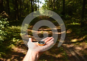 Compass in hand at road in the forest. Tourist compass for orientation on the terrain. Magnetic declination Ñalculator. Map