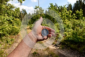 Compass in hand at road in the forest. Tourist compass for orientation on the terrain. Magnetic declination Ñalculator. Map