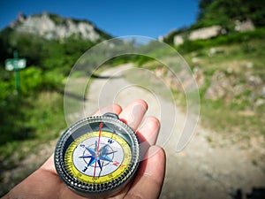 A compass and hand on road in mountains