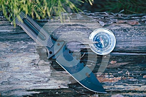 Compass and knife on the background of nature. Traveling concept.