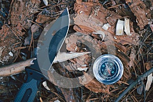 Compass and knife in forest on the ground. hunting concept.