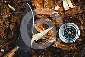 Compass and knife in forest. hunting and hiking concept.