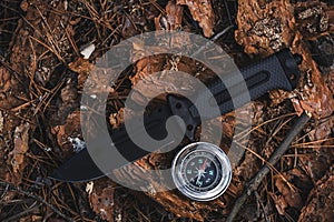 Compass and knife on ground in forest. Adventure and travel concept.