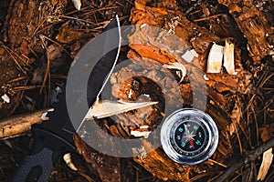 Compass and knife on a log in the forest. Travel concept.