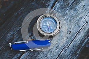 Compass and knife for survival in forest on log.