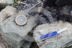 Compass and knife for survival on stones an extinct fire. Hike in the wild.