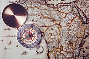 Compass lies on an old map. Orientation on the ground by compass