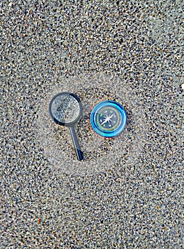 Compass and magnifier on sand