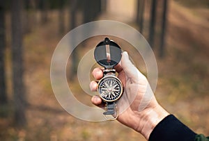 Compass in manâ€™s hand in forest for searching for right direction