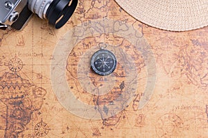 Compass on map with vintage camera and hat