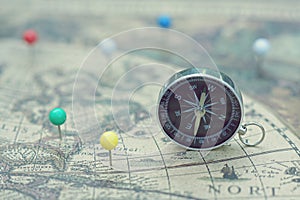 Compass and marking pins on blur vintage map, journey concept photo