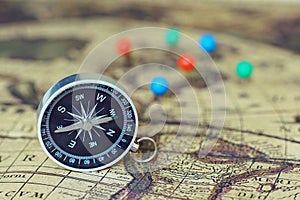 Compass and marking pins on blur vintage world map, journey concept, copy space