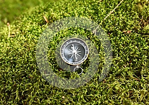 Compass on moss in forest. Tourist compass for orientation on the terrain. Magnetic declination Ñalculator. Historical explorer
