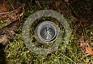 Compass on moss in forest. Tourist compass for orientation on the terrain. Magnetic declination ?alculator. Historical explorer