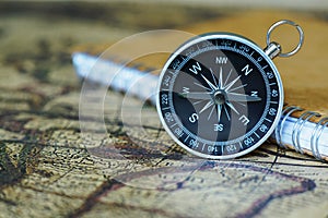 Compass and notebook on blur vintage world map, journey concept