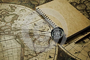 Compass and notebook on blur vintage world map, journey concept, copy