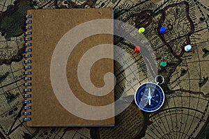 Compass and notebook on blur vintage world map, journey concept, copy space