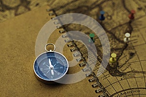 Compass and notebook on blur vintage world map, journey concept, copy space